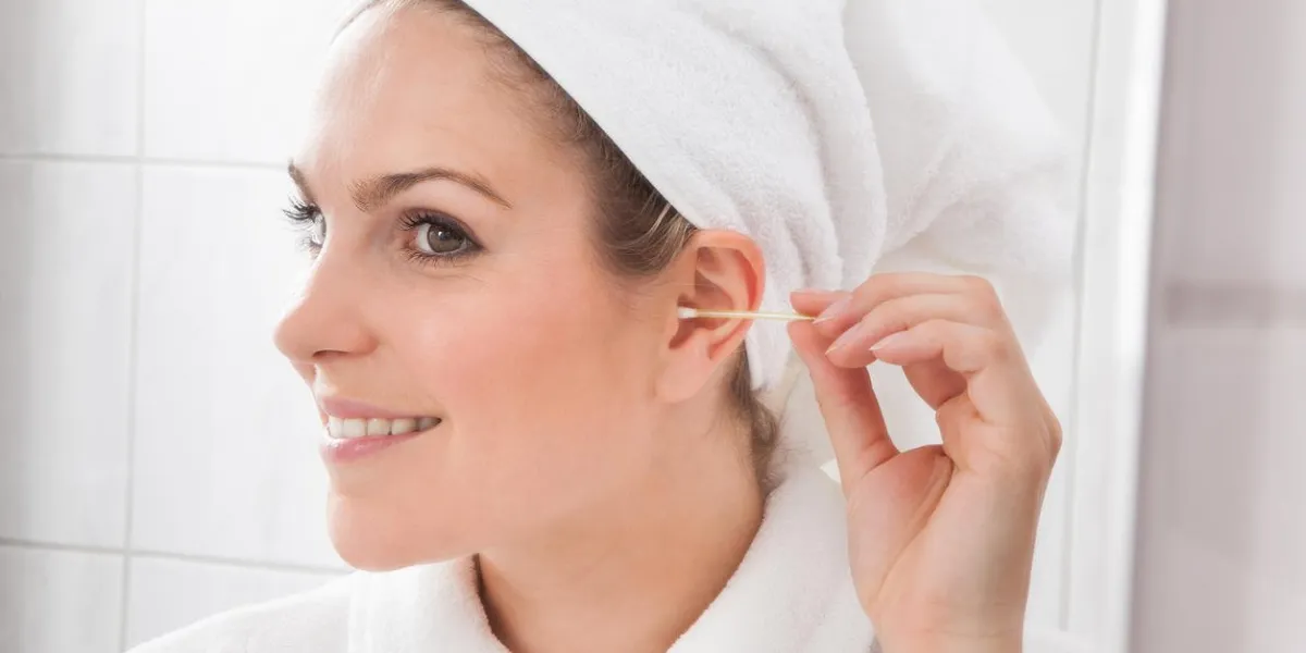 young beautiful woman cleaning ear with cotton swab