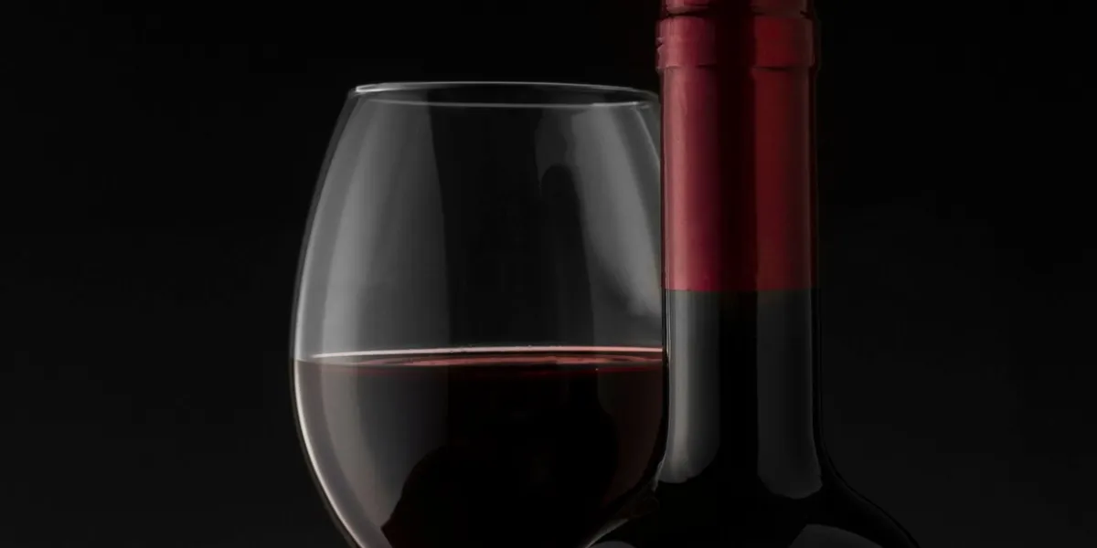red wine bottle and glass on the black background