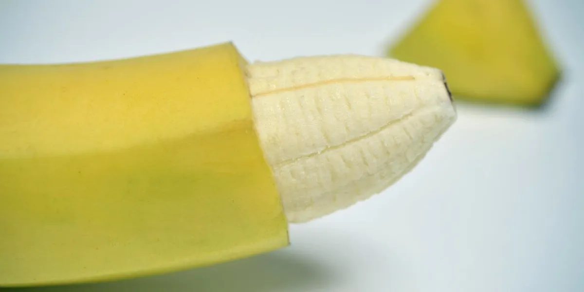 gros plan d'une banane avec la peau de son extrémité enlevée représentant un membre masculin circoncis