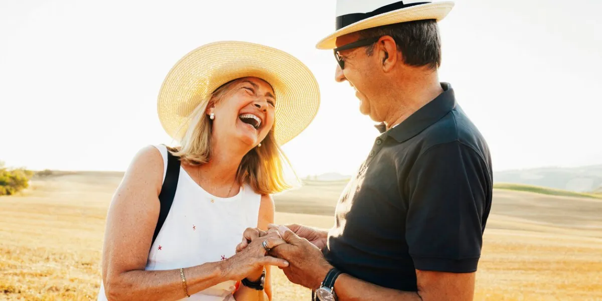 senior couple happy smiling couple, wear stylish clothes, sunglasses and hat, enjoying summer holidays together at field during sunset at tuscany, italy