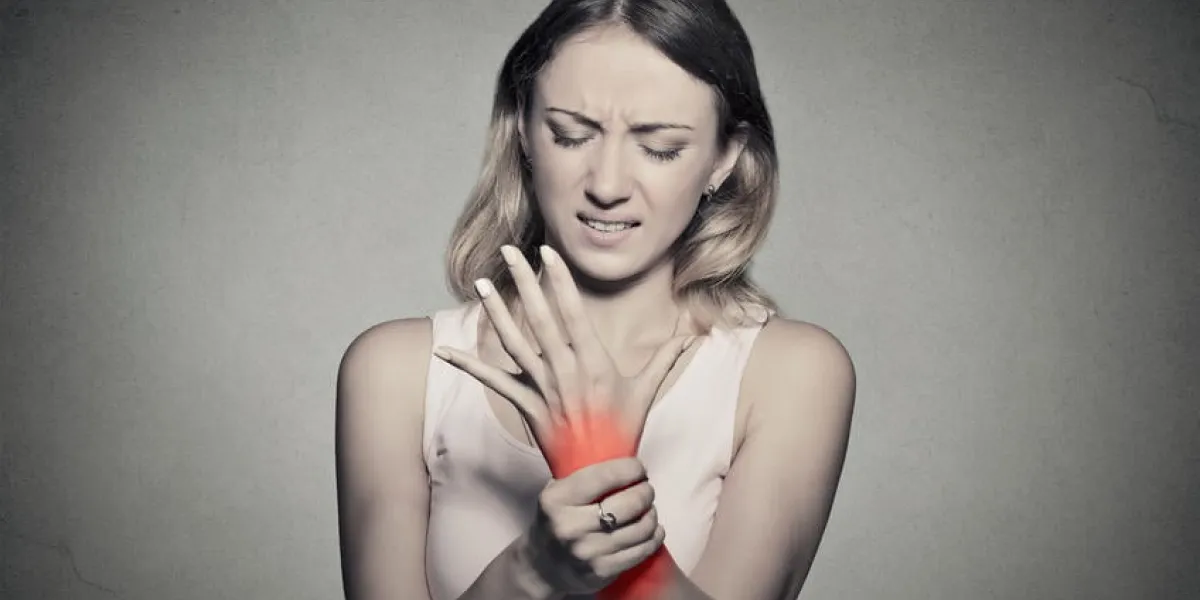 jeune femme, tenue, elle, douloureux, poignet, isolé, sur, gris, mur, fond, entorse, douleur, endroit, indiqué, par, tache rouge, expression négative, visage