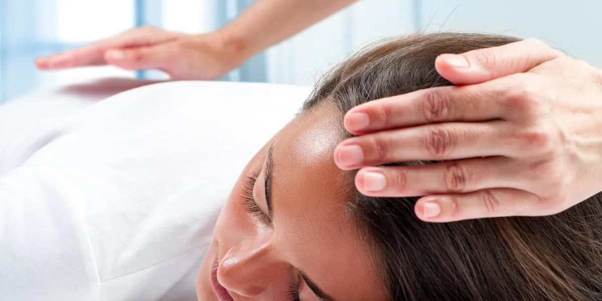 mains de thérapeutes faisant thérapie reiki sur la fille une main sur la tête et une main sur le dos