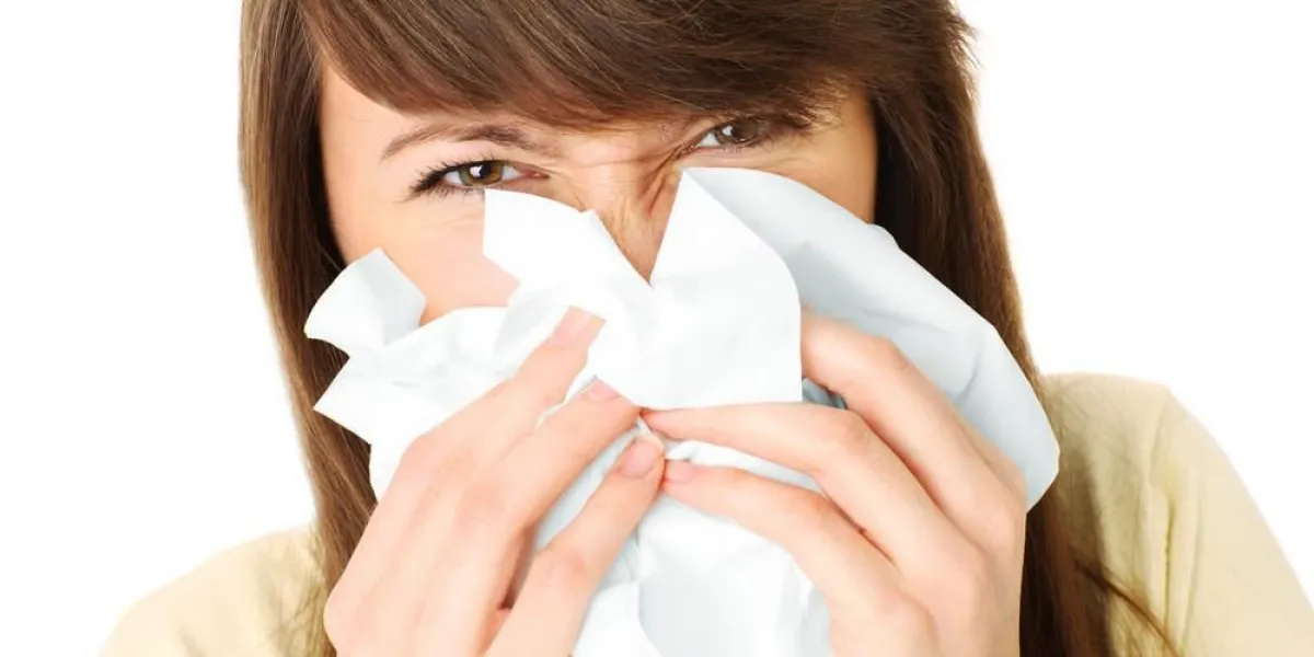 un portrait d'une jeune femme souffle son nez sur fond blanc