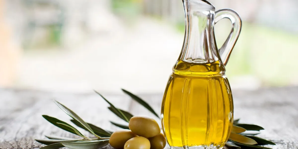 huile d'olive et branche d'olivier sur la table en bois à l'extérieur