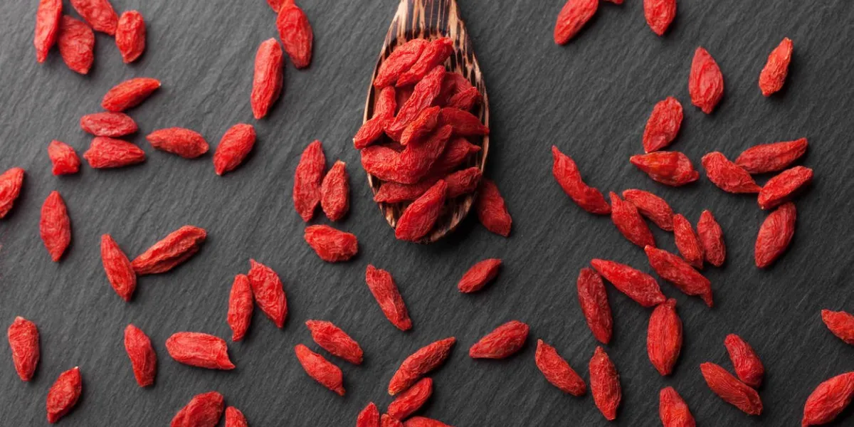 baies de goji séchées sur un fond en bois noir