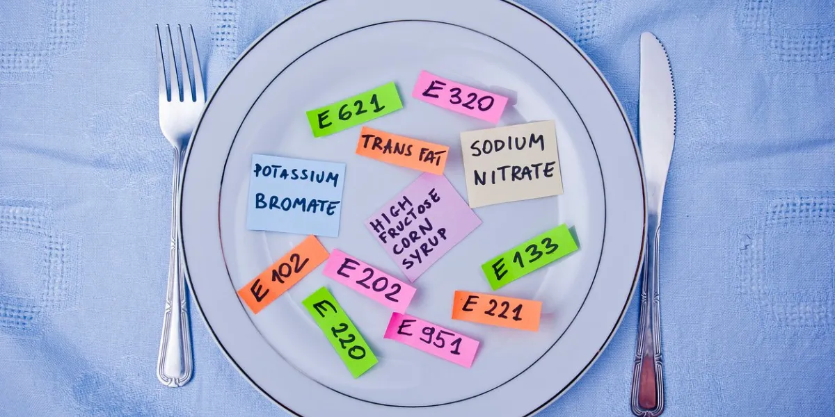 colorful papers imitating food additives on plate with fork and knife, conceptcolorful papers imitating food additives on plate with fork and knife, concept