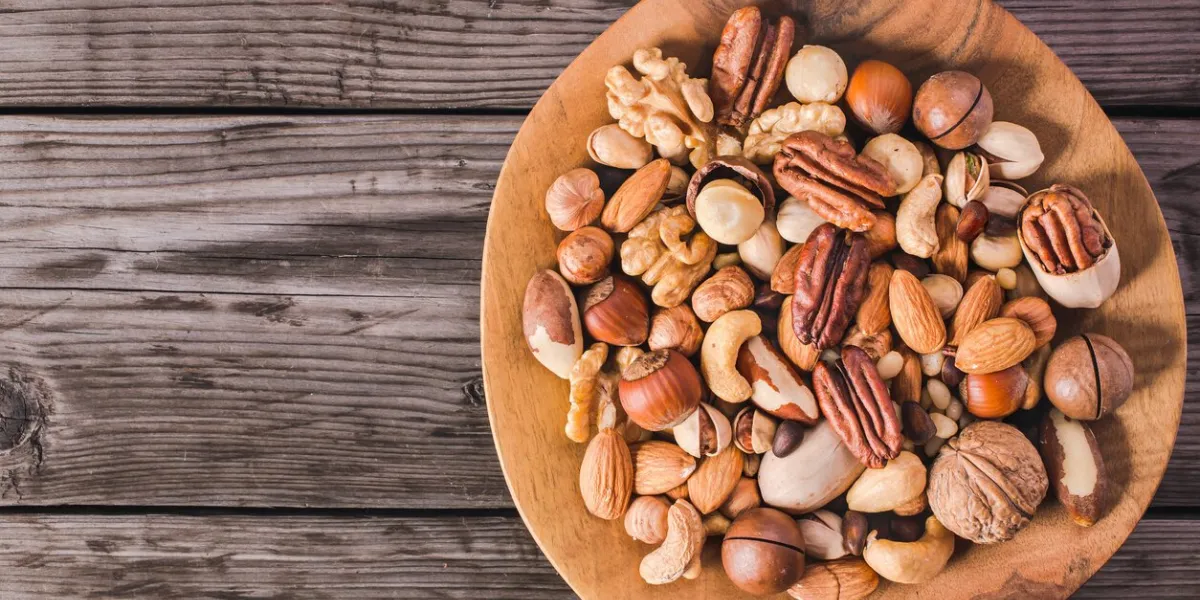 plate of various fresh nuts on old rustic table top view with copy space