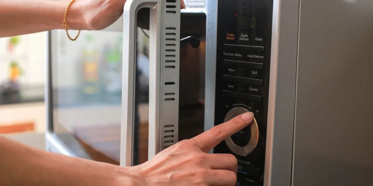 woman's hands closing microwave oven door and preparing food in microwave