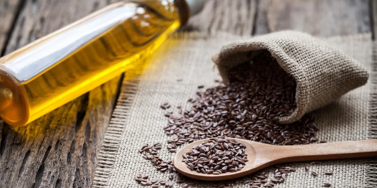 graines de lin dans le sac et l'huile sur fond en bois