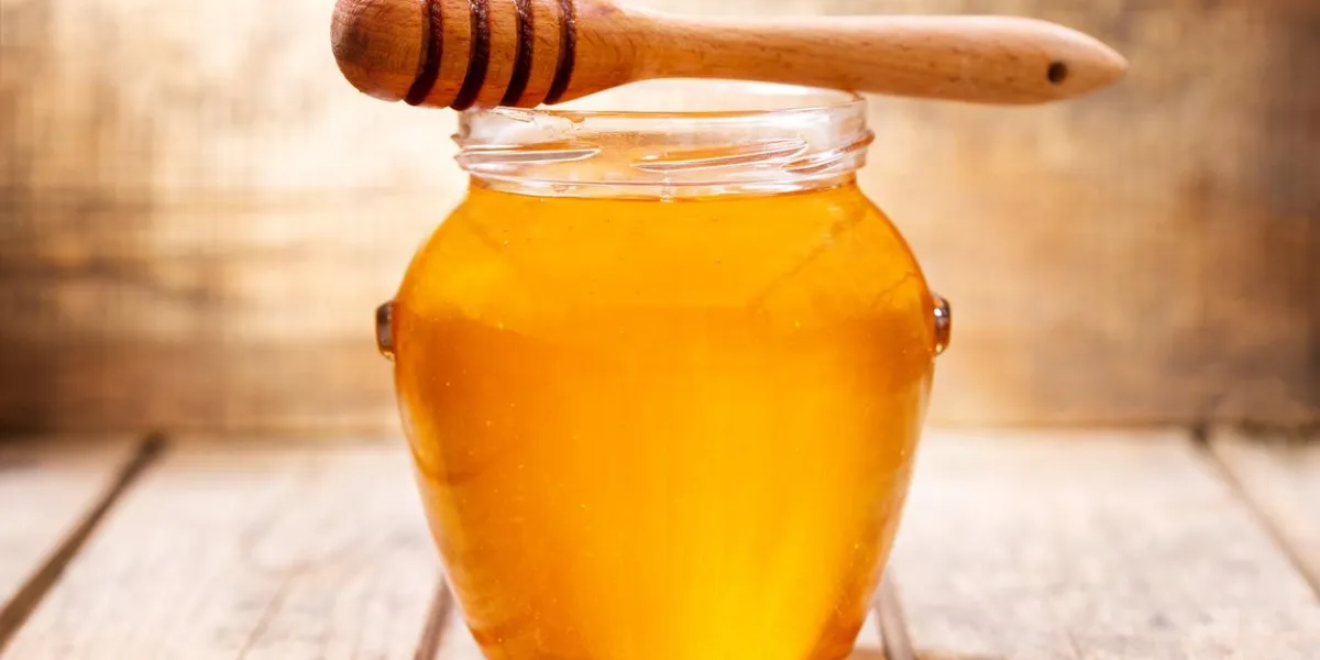 close up of jar of honey on wooden table