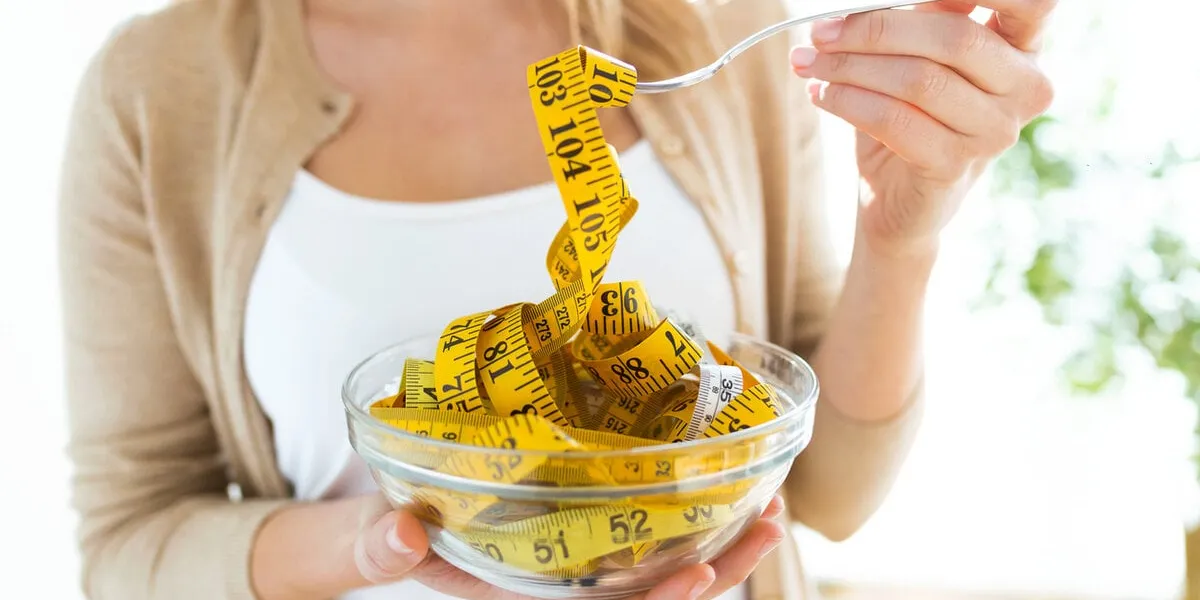 worried cute woman holding bowl with measuring tapes at home