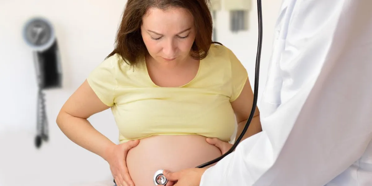 obstétricien écoutant le rythme cardiaque fœtal à travers l'estomac de la mère