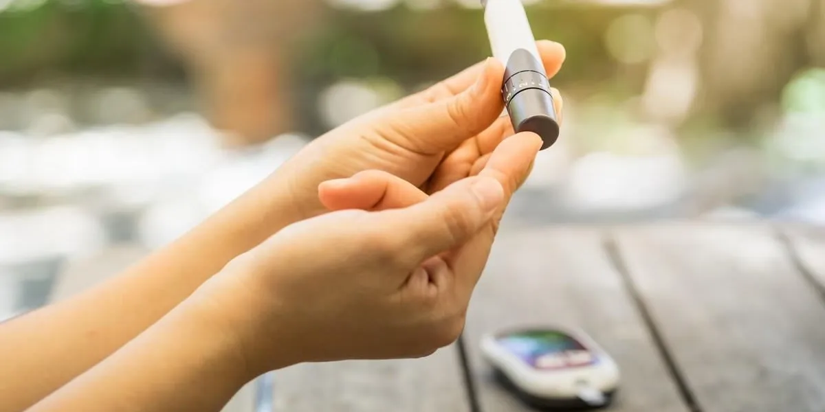 close up of woman hands using lancet on finger to check blood sugar level by glucose meter using as medicine, diabetes, glycemia, health care and people concept