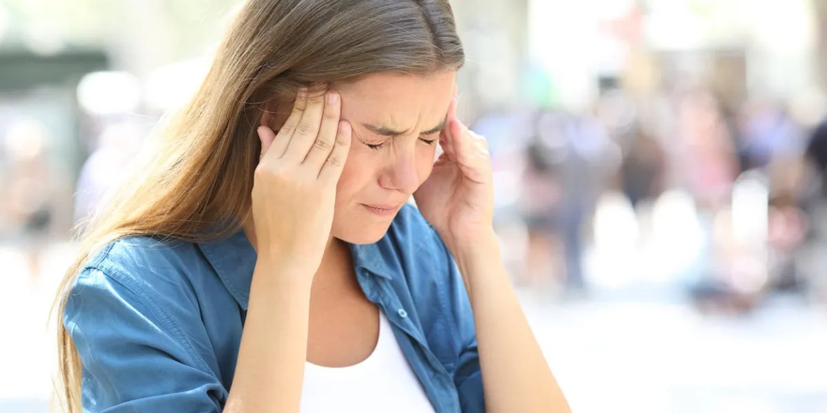 painful girl suffering migraine touching temple in the street