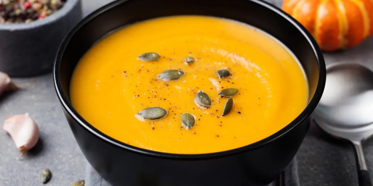 soupe à la crème de citrouille avec des graines de citrouille dans un fond de pierre grise bol noir