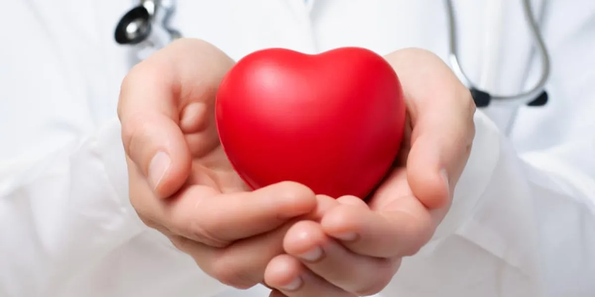 femme médecin protégeant un coeur rouge avec ses mains
