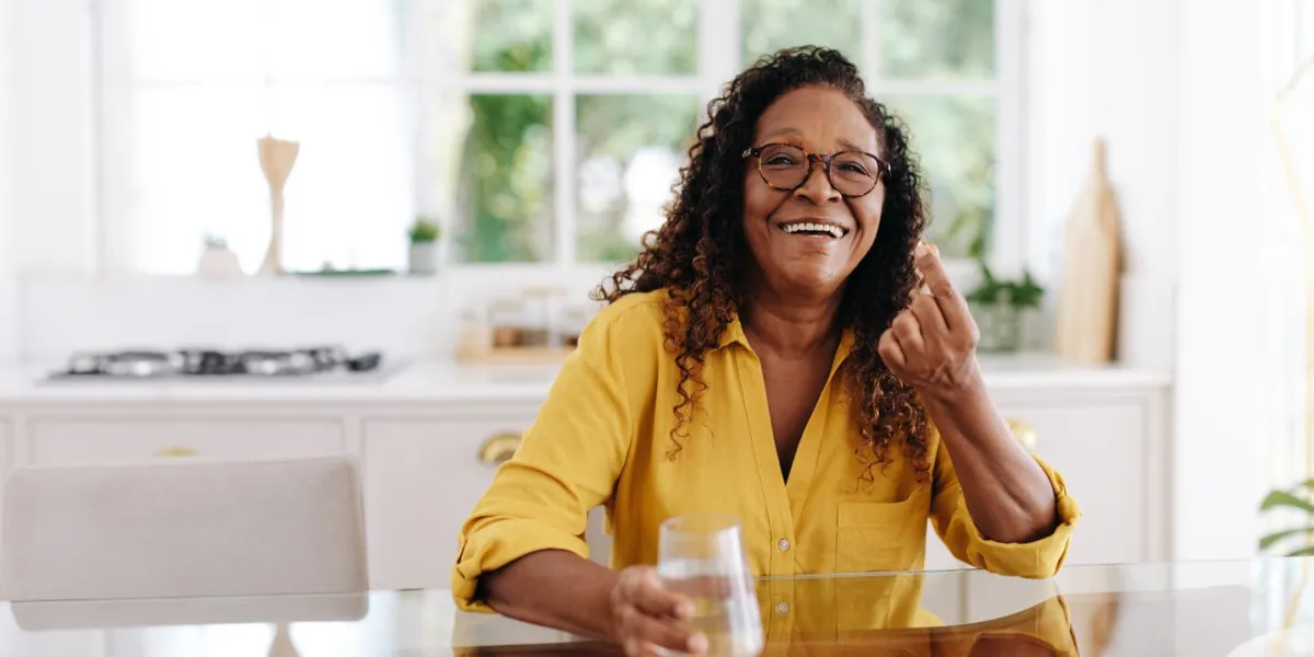 elderly woman smiling happily as she takes nutrition supplements at home aging woman adding enough omega 3 fatty acids into her diet to maintain her health and wellbeing in her golden years