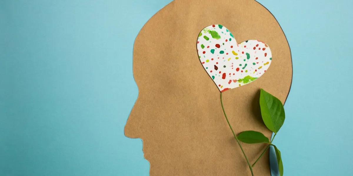 world heart and mental health day paper cut as human head with leaf tree and colorful heart shape flower inside the brain psychology, creativity and positive mind concept