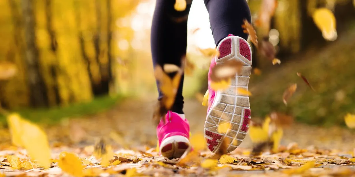 gros plan des pieds du coureur en cours d'exécution des feuilles d'automne