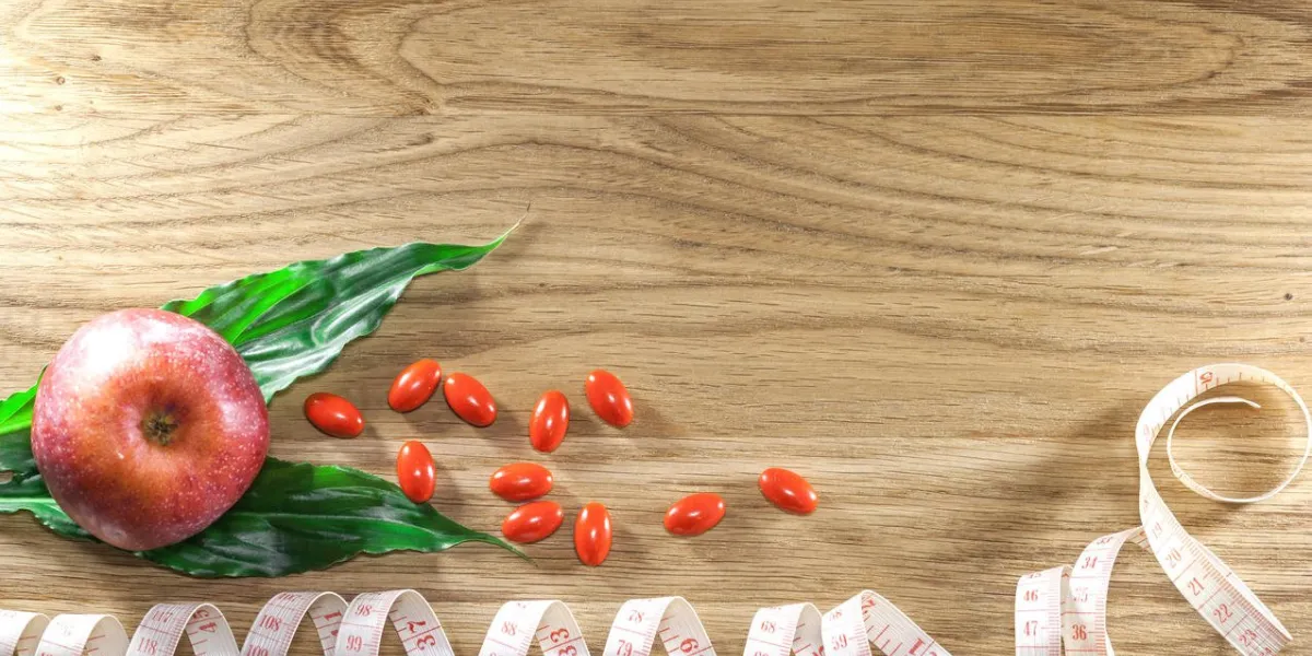 diet pills and apple on wooden background the concept of diet, health