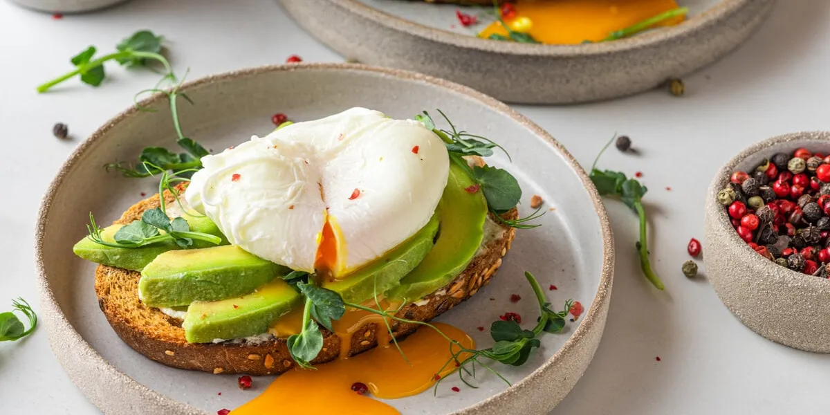 sandwiches with avocado, poached egg, sprouts and cheese for healthy breakfast on white background top view healthy diet food