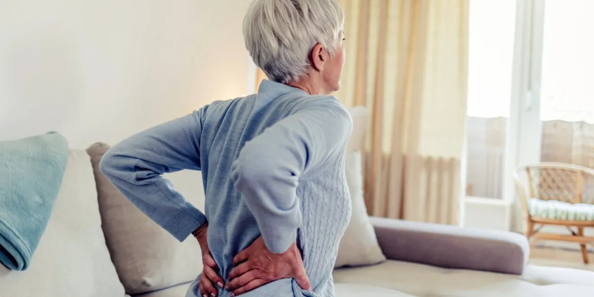 woman feels back pain, massaging aching muscles mature woman feeling morning discomfort in aching back in the living room