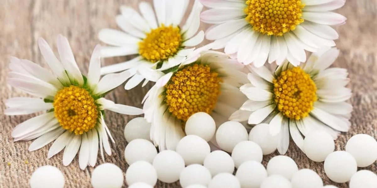 granules homéopathiques sur une table en bois devant des marguerites