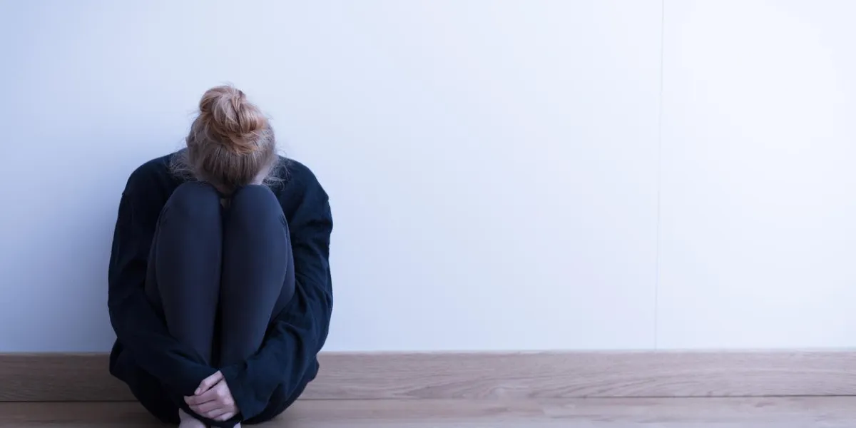 image d'une femme assise recroquevillée sur le sol