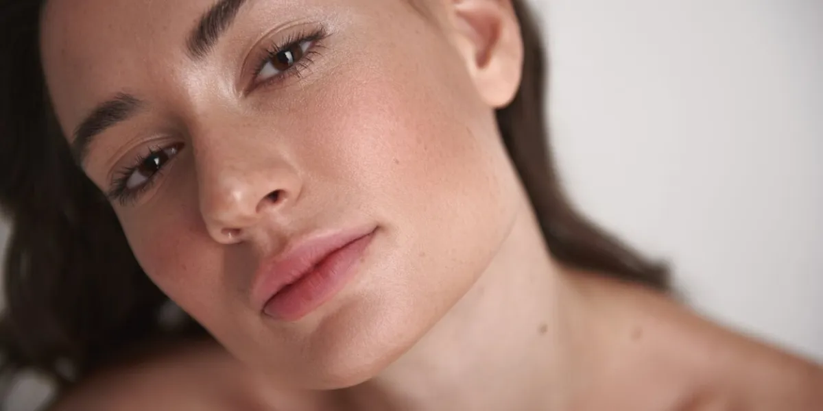 natural look close up top angle portrait of pretty brunette lady with sensual deep glance and nude make-up looking straight on camera isolated on white