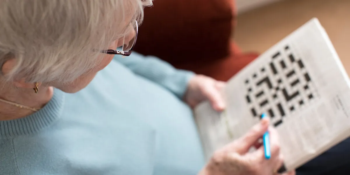 senior woman doing crossword puzzle at home