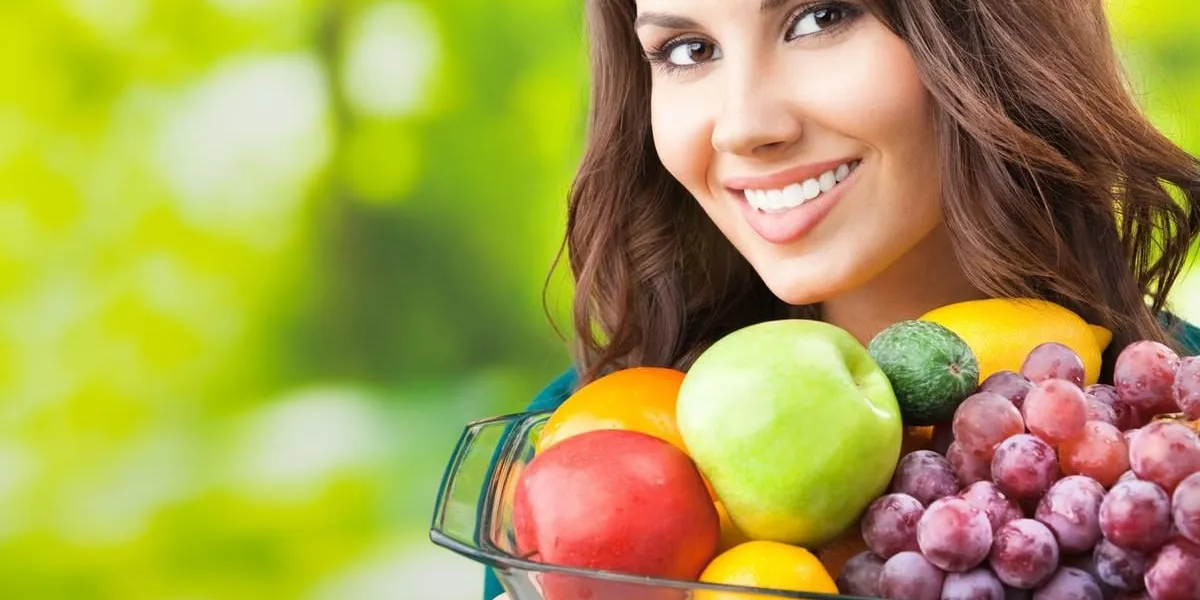 young happy smiling woman with plate of fruits, outdoors, with copyspace for text or slogan