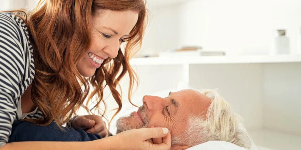 middle aged lovely woman lying on happy senior man and caresses him handsome old man and attractive woman enjoying spending time together while lying in bed mature smiling couple in love at home, copy space