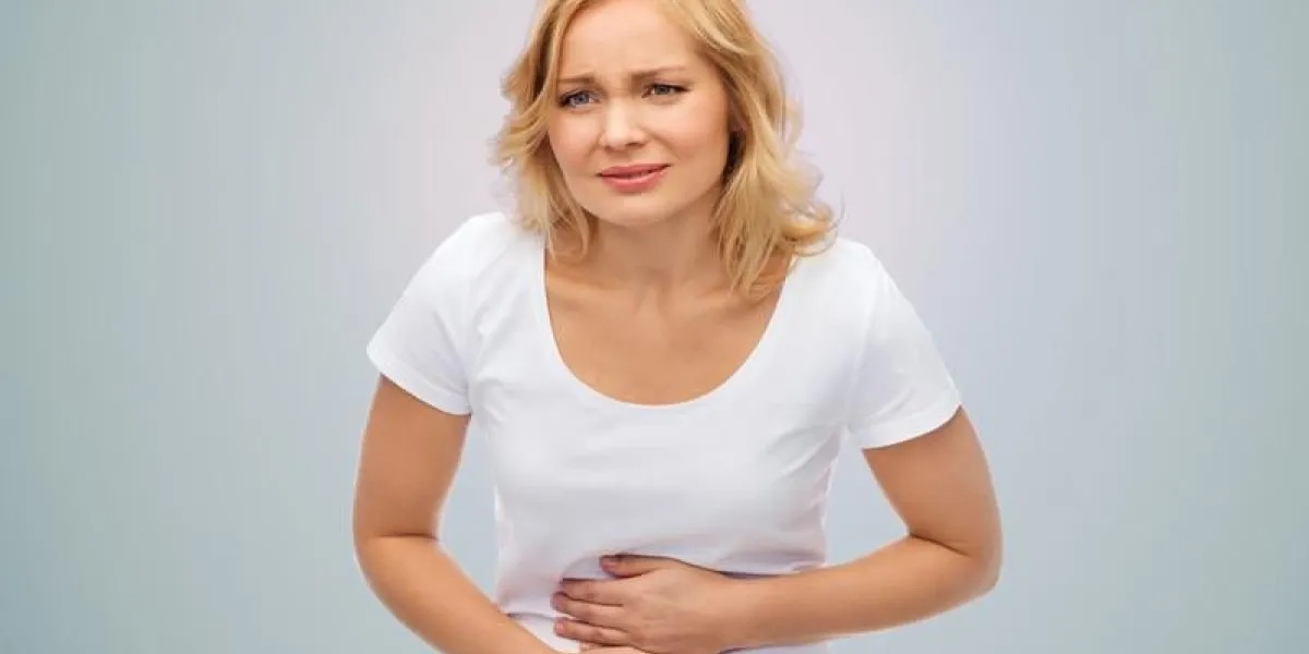 personnes, santé et concept de problème - malheureuse femme souffrant de maux d'estomac sur fond gris