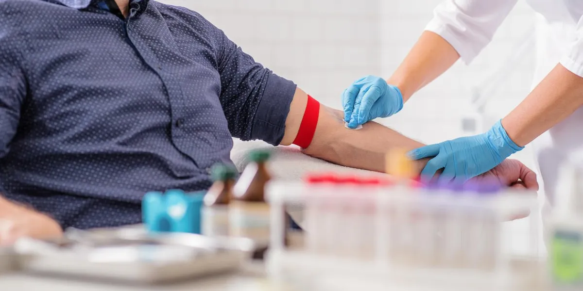 close up of nurse disinfecting male arm before blood test man is sitting on chair near medical set