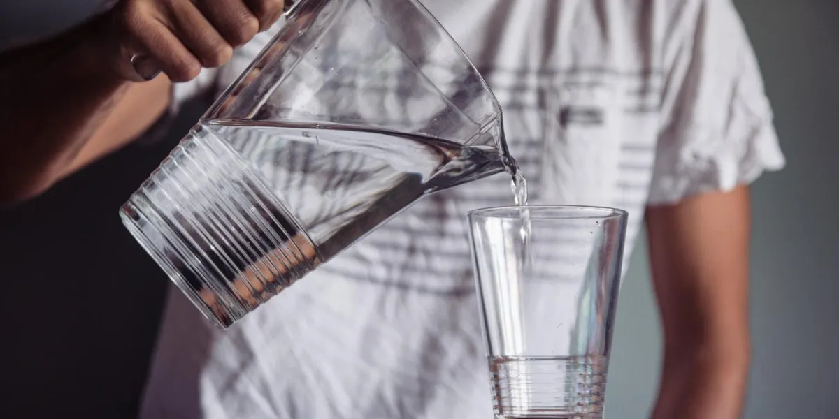 man pouring water into a glass