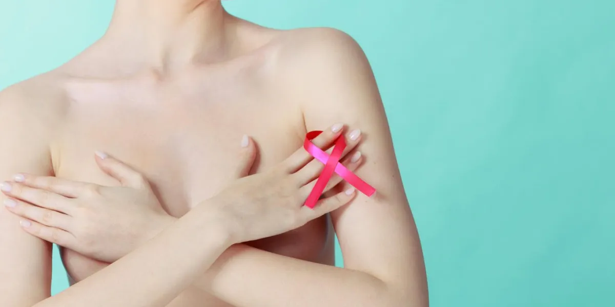 concept de sensibilisation de soins de santé, de médecine et de cancer du sein jeune femme nue avec le symbole de ruban rose couvrant sa poitrine, sur bleu