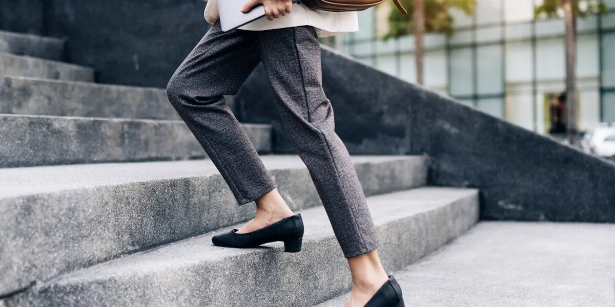 close up legs of businesswoman hurry up walking she is late time female business people holding laptop go to office in the modern city foot step on staircase