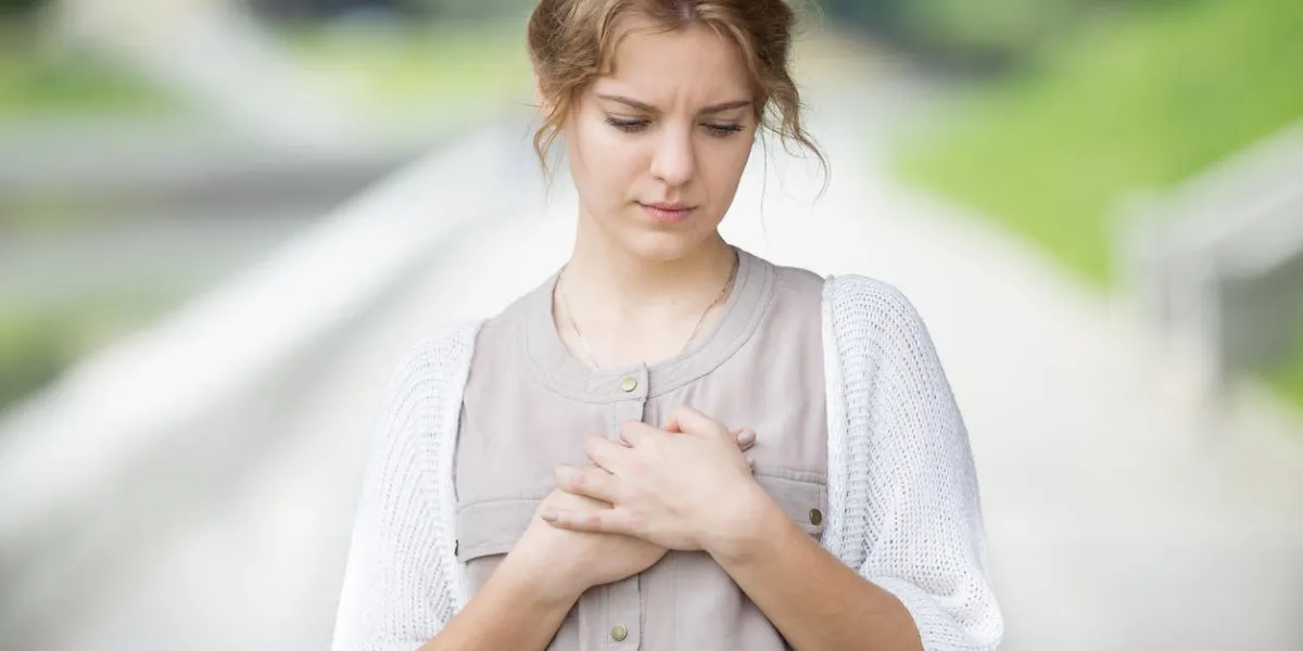 portrait de belle femme stressée marchant dans la rue et toucher sa poitrine avec une expression triste ou avoir mal au coeur modèle attrayant souffrant de douleur à l'extérieur dans le parc de l'été