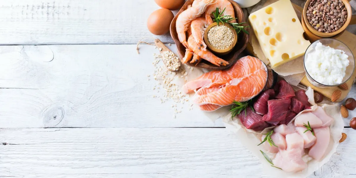 assortment of healthy protein source and body building food meat beef salmon chicken eggs dairy products milk cheese yogurt beans quinoa nuts oat meal copy space background, top view flat lay