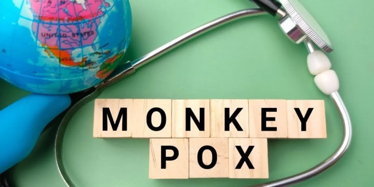 stethoscope,earth globe and wooden cube with the word monkey pox on green background