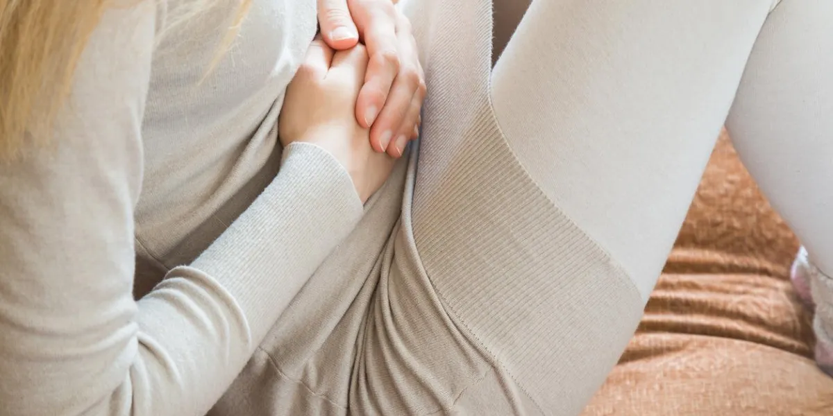 woman's hand touching her belly because she suffering from abdominal pain at home in the bed stomach ache problems and solution concept