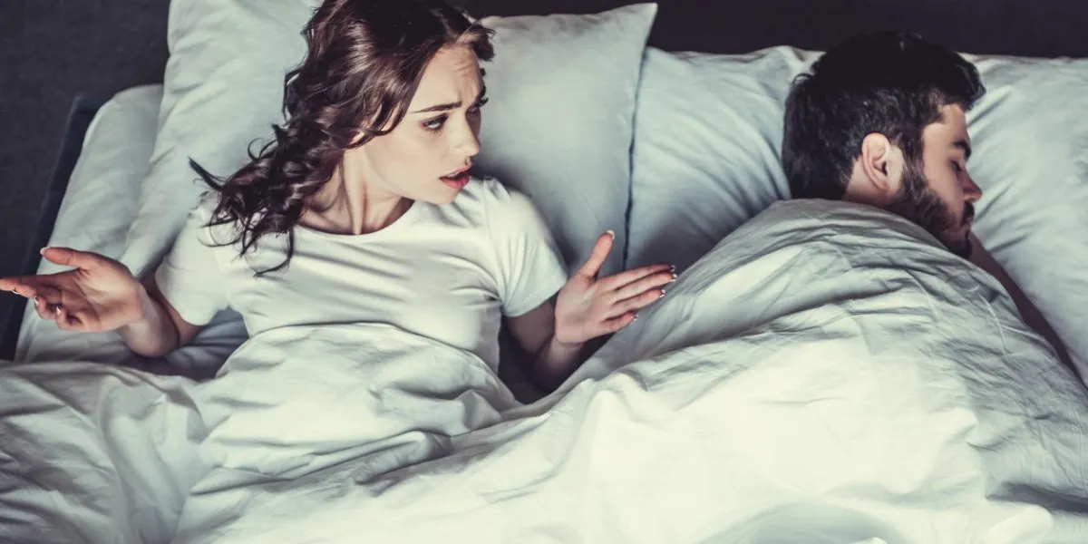 dissatisfied young girl and her boyfriend sleeping in bed
