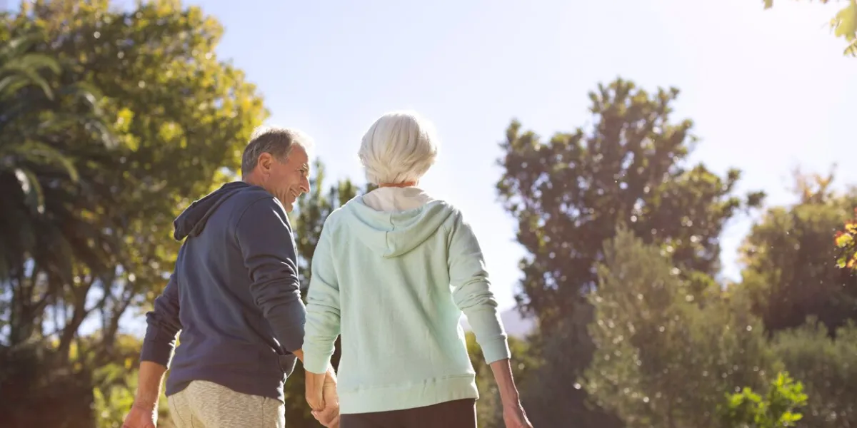 senior couple holding hands and walking in park