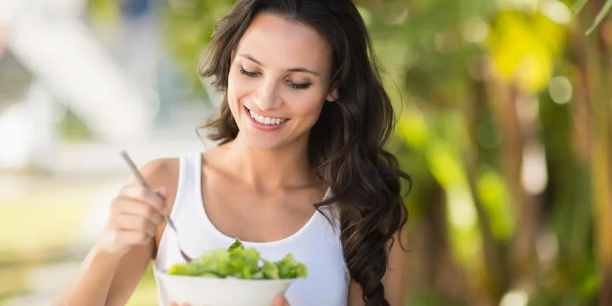 jolie brune mangeant bol de salade sur une journée ensoleillée