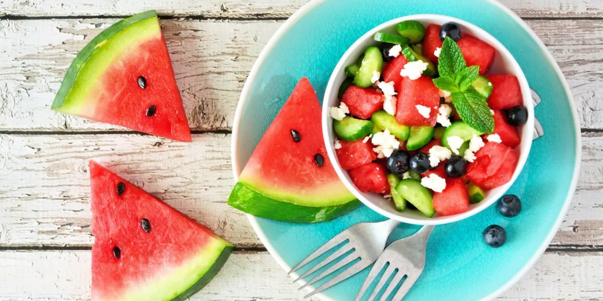 watermelon salad with cucumber, blueberries and feta cheese top view table scene on a white wood background