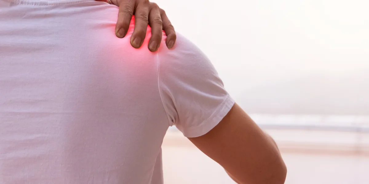 the man who is pain in the shoulder and uses the hand to massage to get the pain