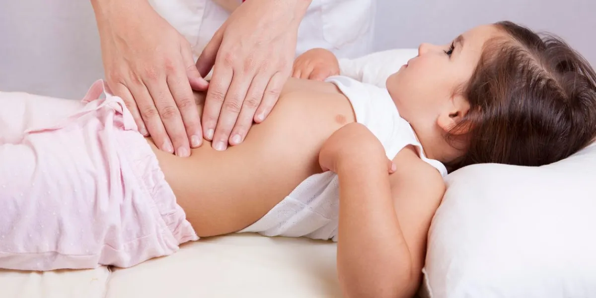 pédiatre faisant l'examen abdominal avec les mains