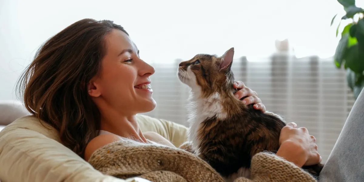 portrait of young woman holding cute norwegian cat with green eyes female hugging her cute long hair kitty background, copy space, close up