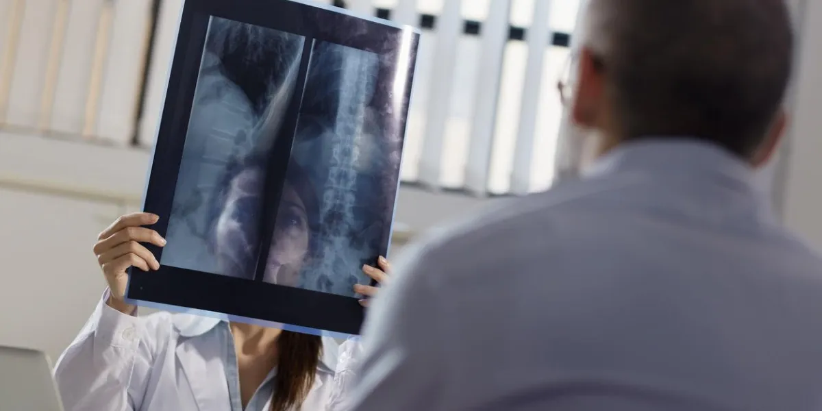 milieu adulte femme au travail en tant que médecin au bureau et en examinant les rayons x avec le patient