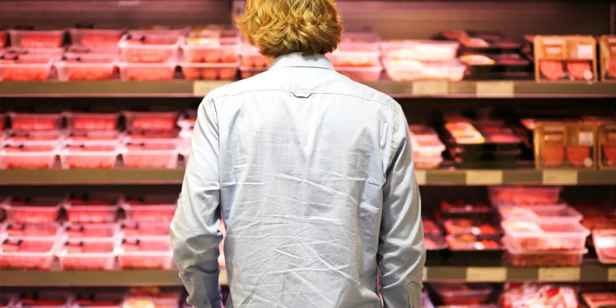 teenager purchasing a packet of meat at the supermarket